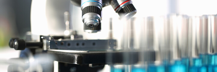 Close up of laboratory glass microscope near medical test tubes in holder. Chemistry and biology concept