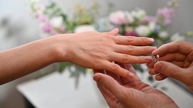 Groom putting on wedding ring on bride hand. Slow motion footage
