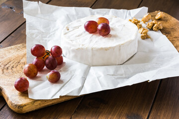 Camembert cheese with red grapes and walnuts, close up
