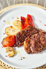 Hot Rib eye steak on white plate. Garnish grilled vegetables. Barbecue restaurant menu.
