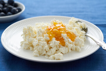 Plate of fresh cottage cheese, breakfast with dairy products, protein food. Blue Linen Crumpled Tablecloth, bright contrast, close up