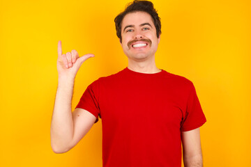 Young Caucasian man wearing red t-shirt standing against yellow background showing up number six Liu with fingers gesture in sign Chinese language