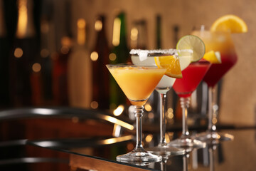 Different delicious cocktails on black table in bar. Space for text