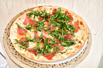 Italian pizza with duck from wood-burning stove. lunch in an Italian restaurant. Table near to a large window.