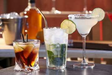 Different delicious cocktails on grey table in bar