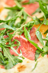 Italian pizza with duck from wood-burning stove. lunch in an Italian restaurant. Table near to a large window.