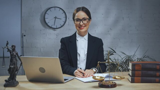 Smiling insurance agent sitting near laptop, scales and books