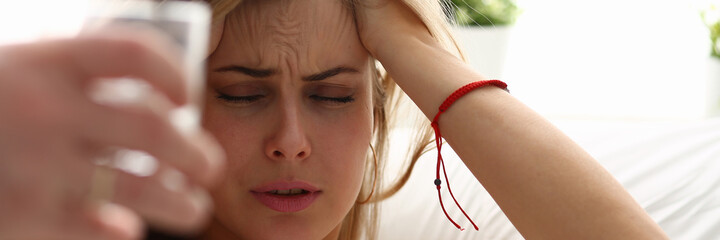 Pretty lady going to take a pill for headache while lying in bed after the hangover and holding hands behind her head