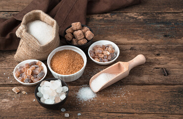 Different types of sugar on a natural wooden background. Side view with copy space. Grocery background.