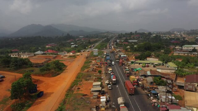 Aerial village vendors trucks highway Ghana Africa pt 3 4K. Busy congested market area and truck parking in rural village. Survive in low income poverty of Africa. Vehicles roadside market shops.