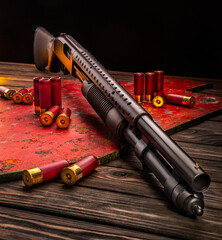 Classic pump action shotgun and cartridges for it. A 12-gauge smoothbore gun on a wooden table,...