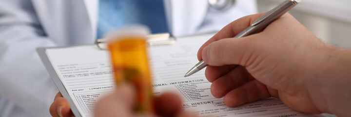 Close up of male patient filling out a questionnaire before prescribing treatment in a clinic