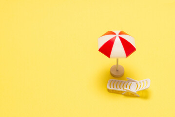 Two sun loungers and a red umbrella on a yellow background.