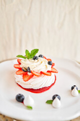 Pavlova is a meringue-based dessert with a crisp crust topped. Decorated strawberry, mint leaf, blueberry and whipped cream. Restaurant sweet food