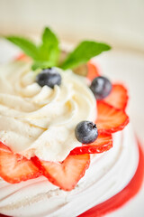 Pavlova is a meringue-based dessert with a crisp crust topped. Decorated strawberry, mint leaf, blueberry and whipped cream. Restaurant sweet food