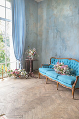 cozy living room interior with chic beautiful antique baroque blue furniture, wooden parquet and luxurious flowers. daytime warm soft light.