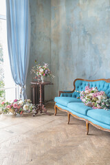cozy living room interior with chic beautiful antique baroque blue furniture, wooden parquet and luxurious flowers. daytime warm soft light.