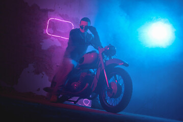 Plakat Motor biker in the neon lights in the old garage.