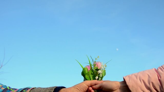 Giving flowers to grandmother. Bouquet in old wrinkled hands close-up. Mothers Day. Congratulate mom. March 8. Congratulations concept. Hand with flowers close-up. Spring bouquet in grandmother's hand