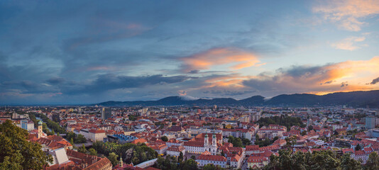 Obraz premium Cityscape of Graz with Mariahilfer church and historic and modern buildings of Graz, Styria region, Austria, at sunset. Dramatic sky, panoramic view