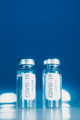 Vaccination against coronavirus COVID - 19. Vial on a blue background close-up. Concept.