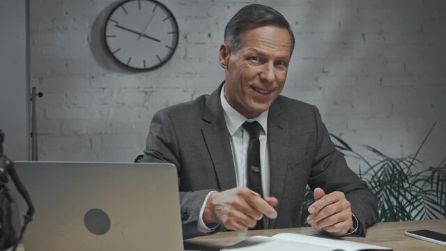 Insurance agent talking to camera near laptop and notebook