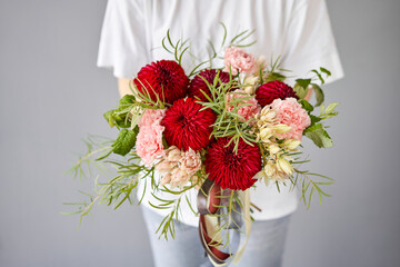 Red tones Beautiful bouquet of mixed flowers in womans hands. the work of the florist at a flower shop. Handsome fresh bouquet. Flowers delivery