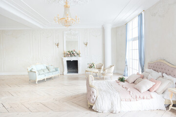 luxurious light interior in the Baroque style. A spacious room with a road chic beautiful furniture, a fireplace and flowers. plant stucco on the walls and light wood parquet