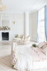 luxurious light interior in the Baroque style. A spacious room with a road chic beautiful furniture, a fireplace and flowers. plant stucco on the walls and light wood parquet