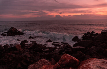 Krajobraz wybrzeża ze skałami nad oceanem z falami na tle pomarańczowego zachodzącego słońca....