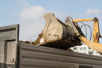 Shovel Tilts Earth In A Low Loader