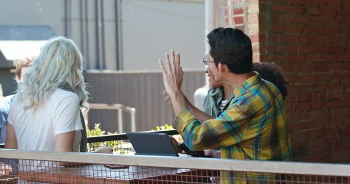 Group of young people working on a digital tablet at an outdoor cafe.