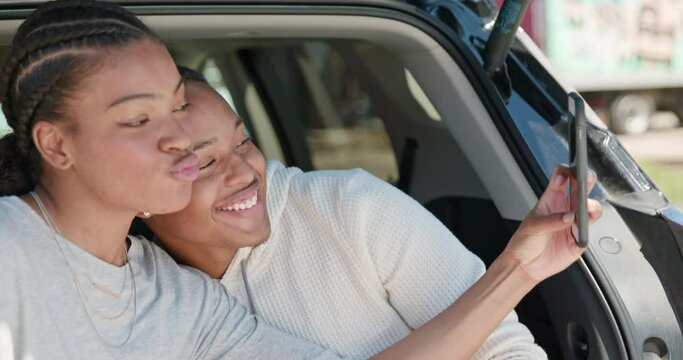 Young African American couple having impromptu picnic lunch in the back of their vehicle, taking selfie with mobile phone 