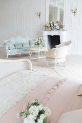 luxurious light interior in the Baroque style. A spacious room with a road chic beautiful furniture, a fireplace and flowers. plant stucco on the walls and light wood parquet