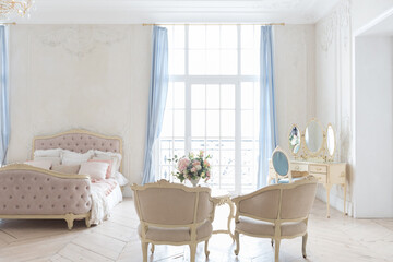 luxurious light interior in the Baroque style. A spacious room with a road chic beautiful furniture, a fireplace and flowers. plant stucco on the walls and light wood parquet