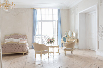 luxurious light interior in the Baroque style. A spacious room with a road chic beautiful furniture, a fireplace and flowers. plant stucco on the walls and light wood parquet