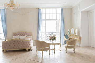 luxurious light interior in the Baroque style. A spacious room with a road chic beautiful furniture, a fireplace and flowers. plant stucco on the walls and light wood parquet