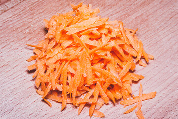 Sliced vegetables for cooking. Vegetables on a round wooden cutting board lying on the kitchen table. Grated carrots.