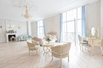 luxurious light interior in the Baroque style. A spacious room with a road chic beautiful furniture, a fireplace and flowers. plant stucco on the walls and light wood parquet