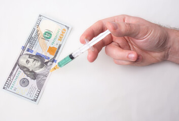 A syringe with green liquid stuck into the figure on the 100 dollar bill
