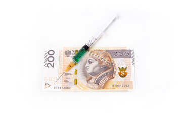 A syringe with a green liquid on the background of a PLN 200 banknote