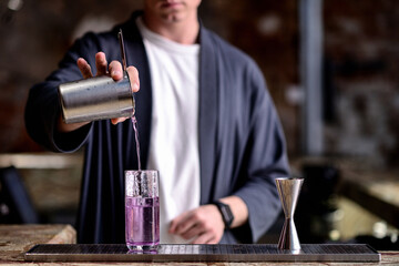 The bartender prepares and pours a cocktail