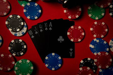 Game chips lie on the table against a red background. Game chips for betting in gambling. Poker chips. Playing cards.