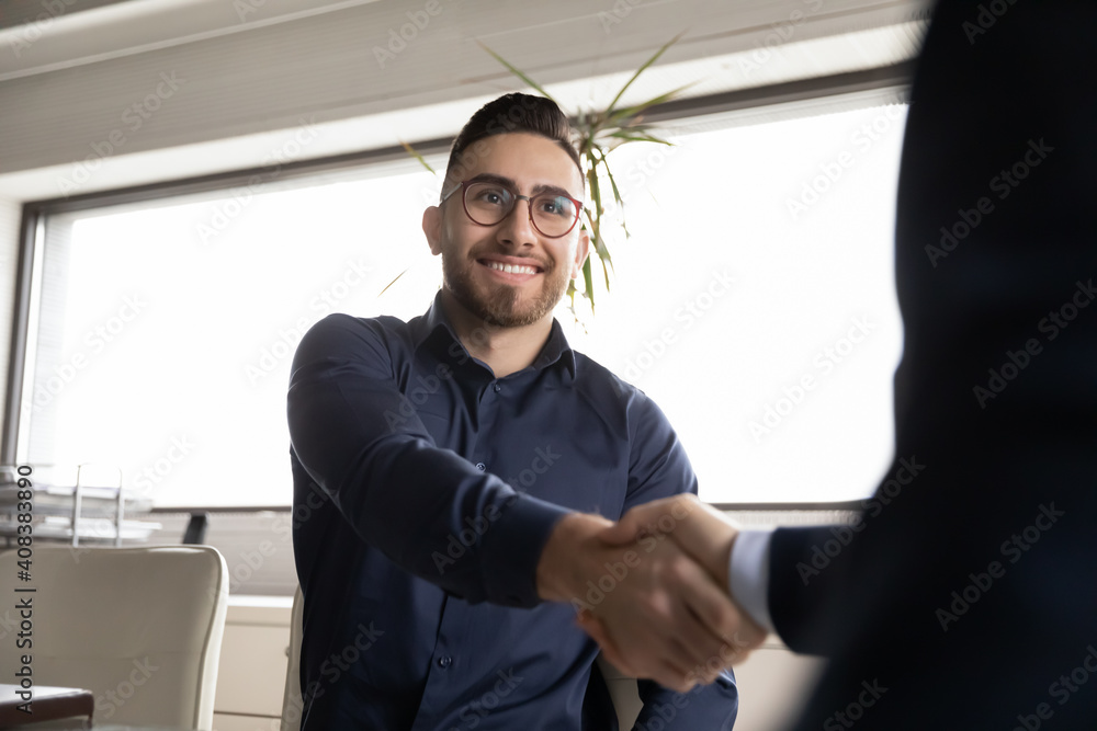 Sticker Close up smiling Arabian candidate wearing glasses shaking employer hand, getting job, hr manager congratulating successful seeker, diverse business partners greeting, good first impression concept