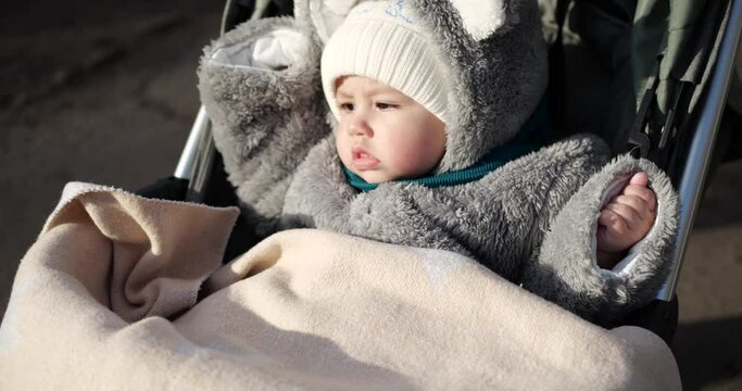 baby boy rides in a stroller in winter in sunny weather. little boy in carriage