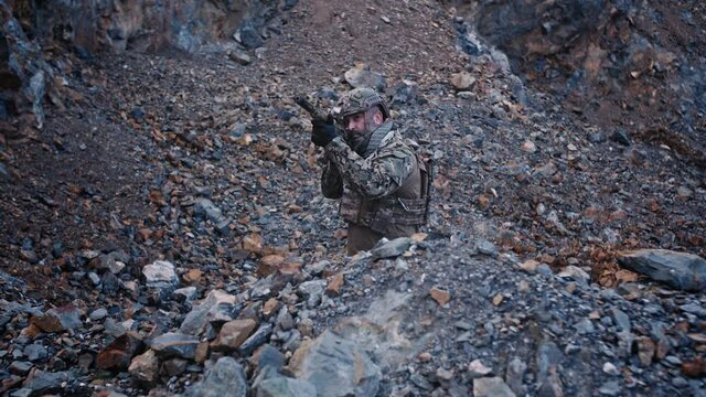 Special force soldier takes aim in a mountain gorge. Military and rescue operation concept.
