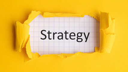 The word strategy appeared behind the torn yellow paper.