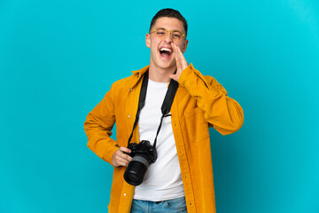 Naklejka premium Young caucasian photographer man isolated on blue background shouting with mouth wide open