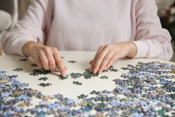 Young woman playing with puzzles at table, closeup