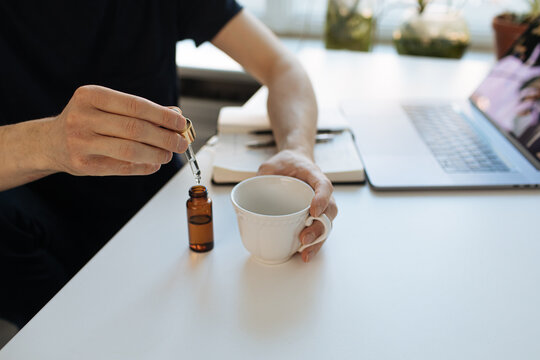 Vitamins and supplements. Hand holding pipette of Hemp herbal oil. Close up man uses CBD oil. Medical cannabis essence. Healthy lifestyle use medical essential tincture for better skin